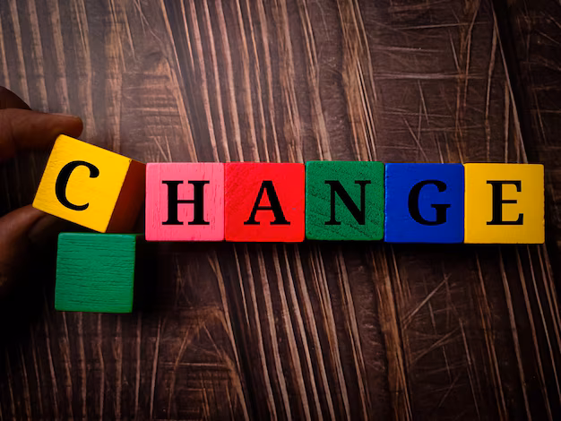 hand-holding-colored-wooden-cube-with-word-change-wooden-table-background_406607-2030